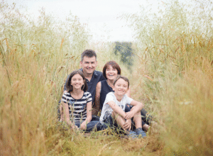 Family laughing in the long grass taken by Horsham Photographer Samphire Photographer