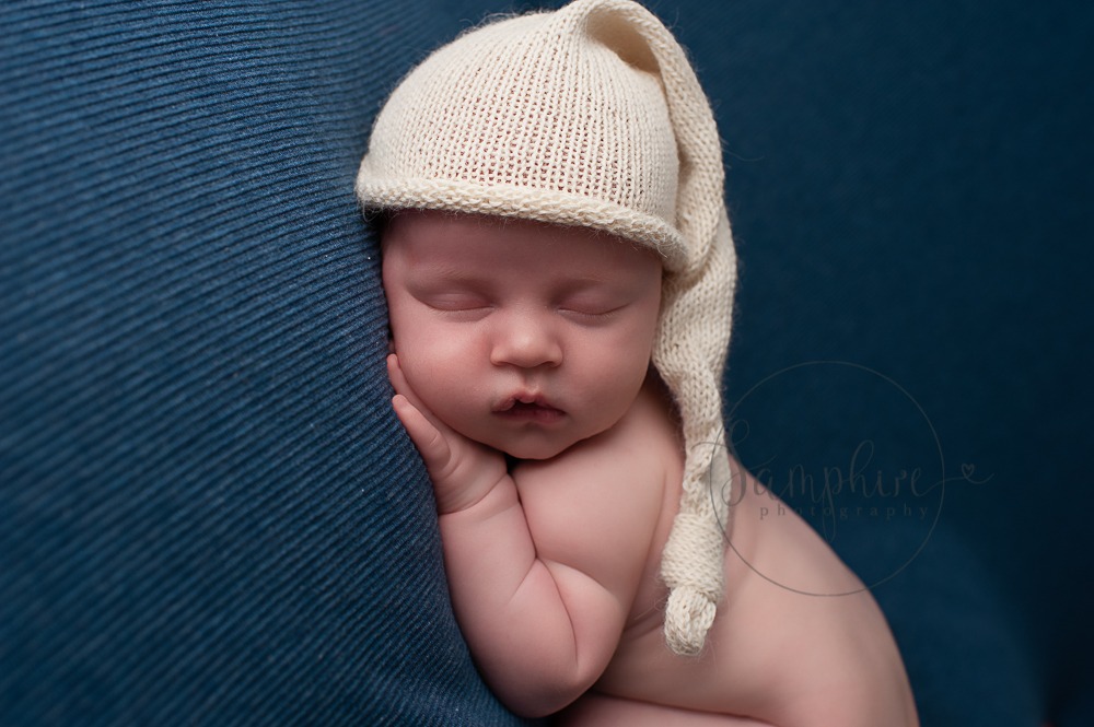 West Sussex Newborn Photographer sleeping baby boy in knitted cream hat on blue by Samphire Photography Horsham