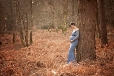 Woodland Maternity and Newborn Session pregant lady blue dress standing outdoors tree Samphire Photography