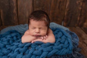 New baby portraits West Sussex blue knitted layers wooden background Samphire Photography