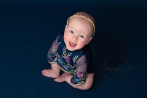 baby photoshoot horsham showing Smiley little girl wearing blue romper