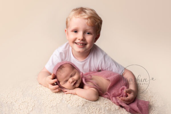 newborn baby shoot with sibling smiling