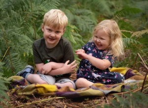 laughing siblings outdoors for woodland photoshoot