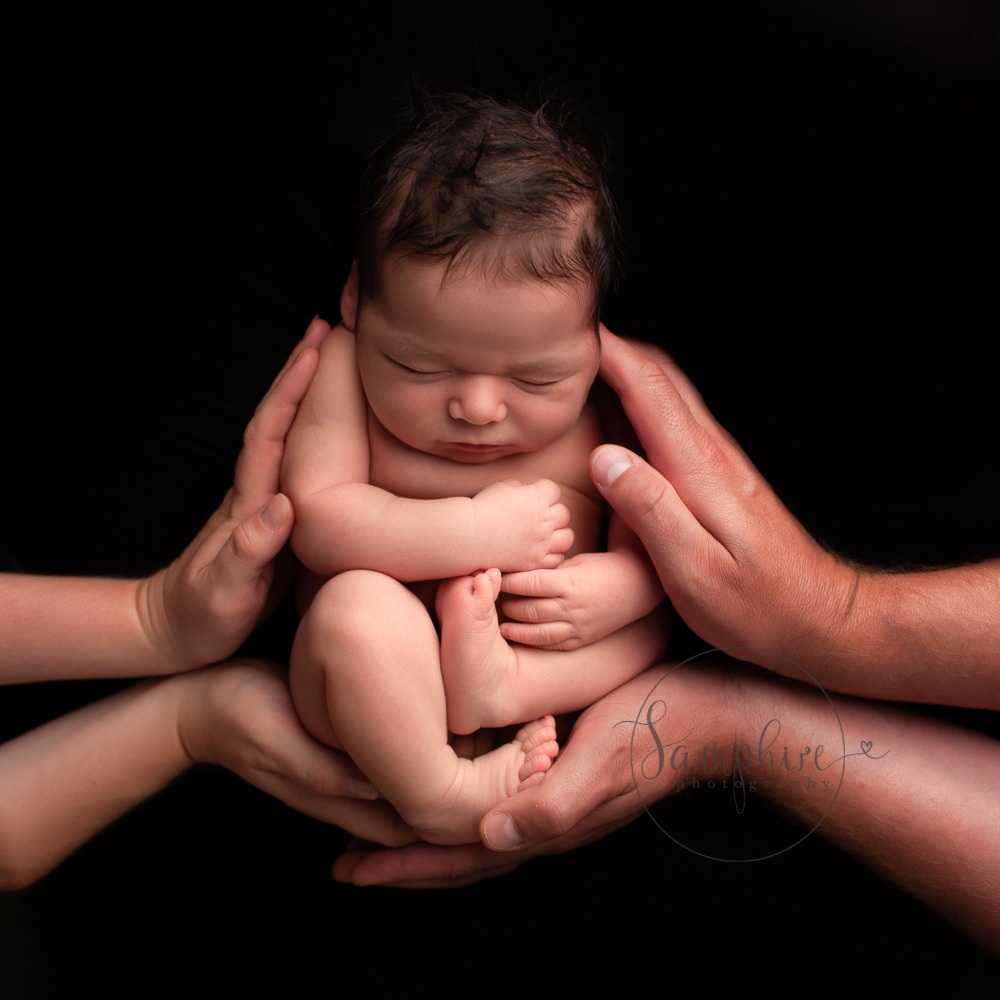 baby in hands during baby photo shoots with experienced newborn photographer Surrey