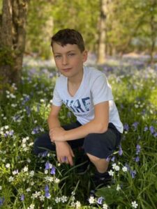 boy crouching among bluebells