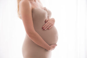 studio portrait of pregnant woman cradling belly