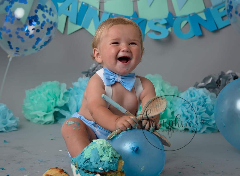 Very happy boy showing what is a cake smash by Samphire Photography