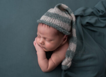 Baby boy in stripy slouch hat at his newborn portrait session