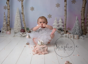 little girl with her foot in the air at her Christmas cake smash in Storrington