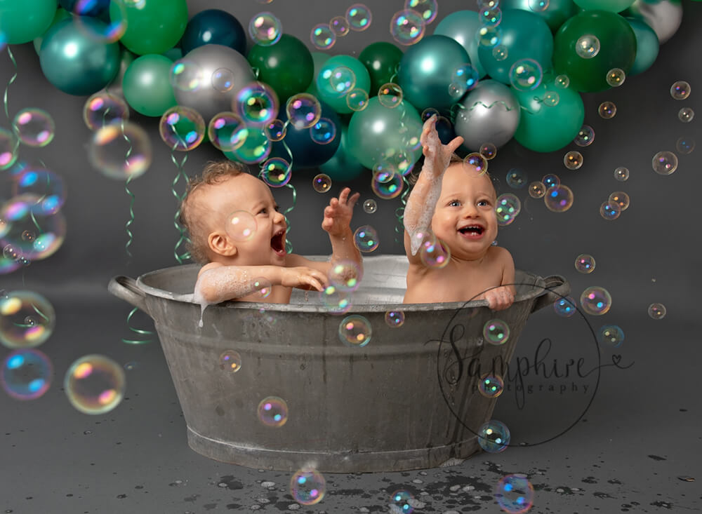 Twin boys in metal bath catching bubbles