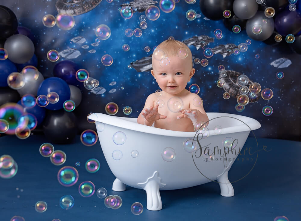 Boy catching bubbles in a victorian bath with a spaceship theme