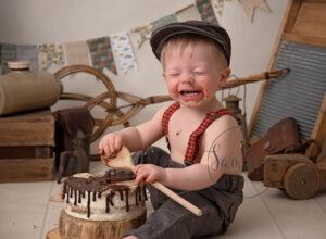 Chocolate faced boy enjoying a cake but what is a cake smash