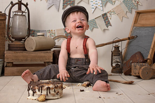Boy in vintage clothing having fun at his cake smash