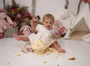 happy girl with cuddly bunnies cake smash