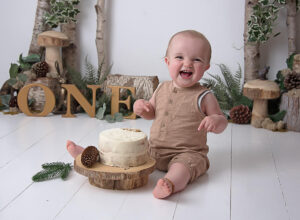 happy boy in woodland theme cake smash