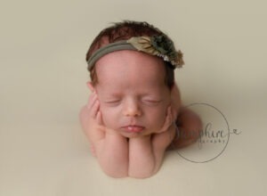 baby girl asleep head on hands wearing green floral headband