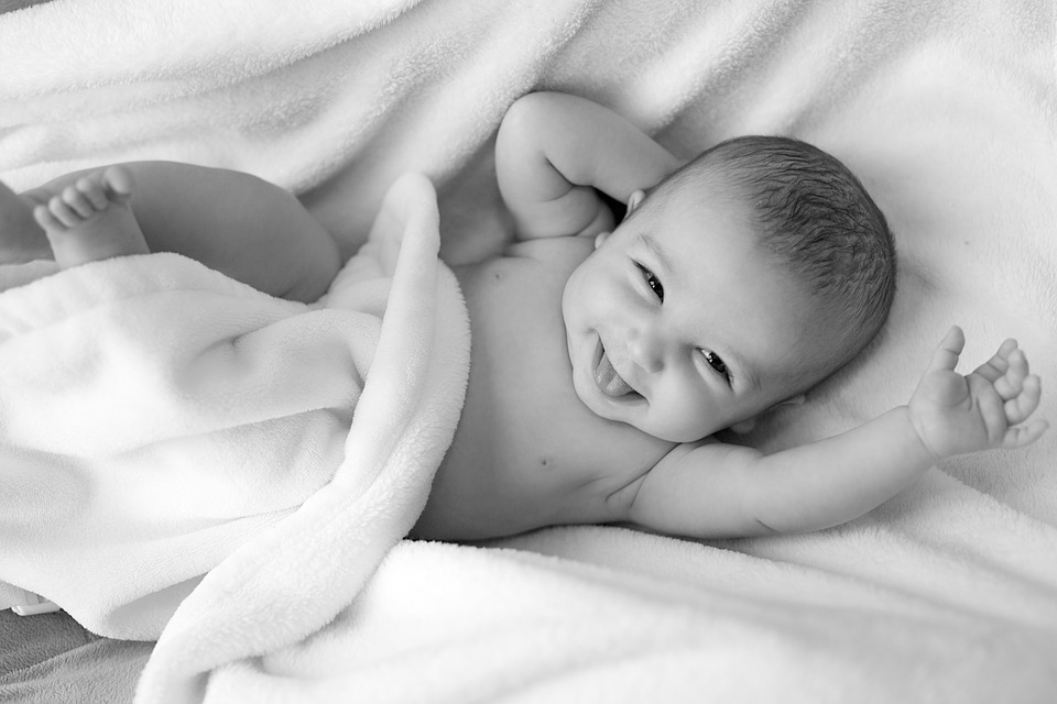 awake smiling baby on white blanket