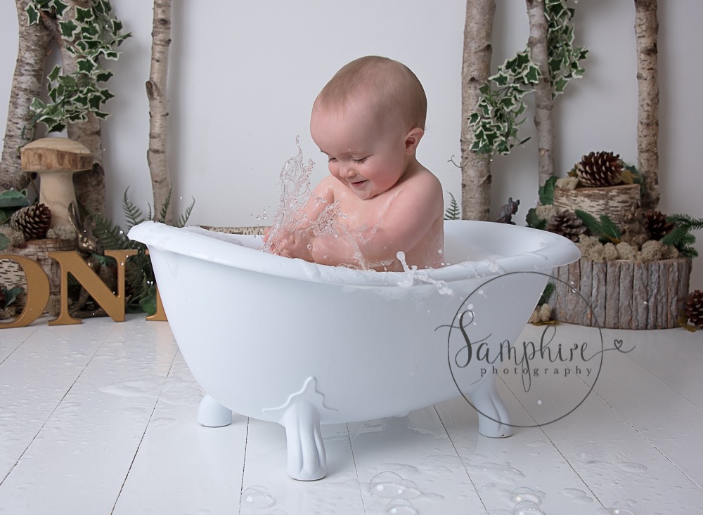 baby splashing in a tub showing how to prepare for a cake smash
