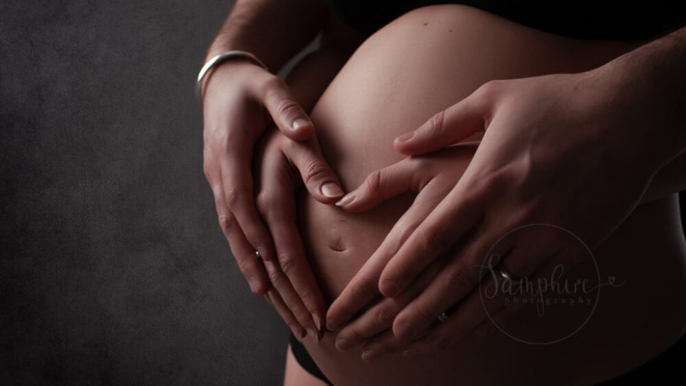 heart shaped hands on pregnant belly