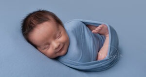 smiley baby boy in blue by sussex photography studio