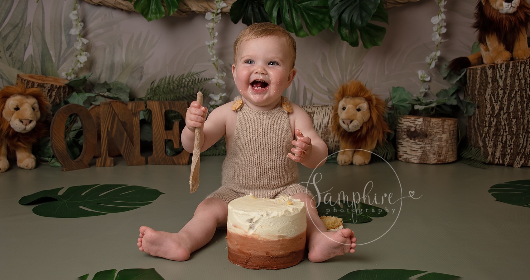 happy one year old boy with jungle themes cake smash in sussex
